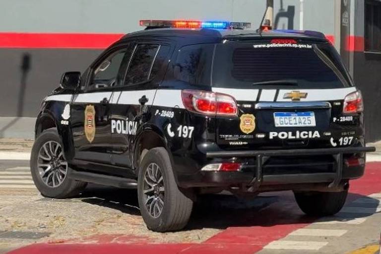 A imagem mostra dois veículos policiais estacionados em uma rua. Os carros são de cor preta e branca， com luzes de emergência acesas. Ao fundo， há um sinal de trânsito e placas de rua， incluindo uma que diz 039;Rio Branco039;. O ambiente é urbano， com árvores e prédios ao redor.