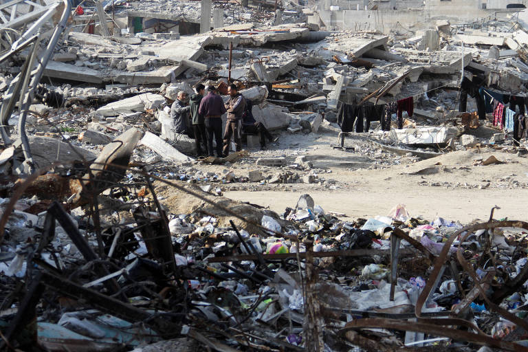 Palestinos em meio a escombros de casas destruídas em ataques aéreos na Cidade de Gaza