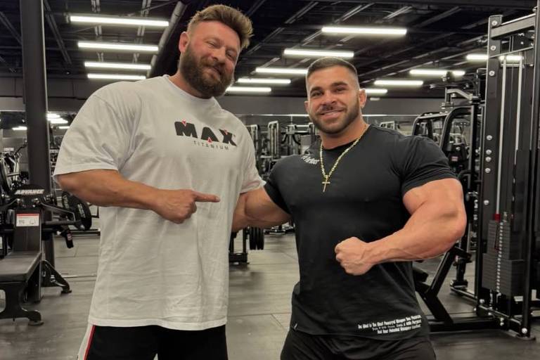 Treinador e atleta posam para foto em academia