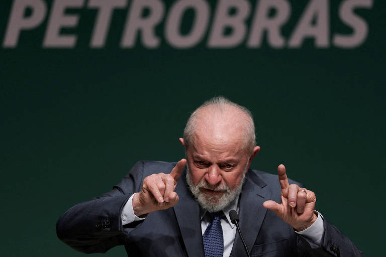 Lula discursa com os dois dedos indicadores em rista; ao fundo， há o logotipo da Petrobras