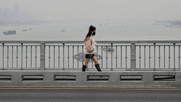 Uma mulher caminha na ponte sobre o rio Yangtze em Wuhan， na província central de Hubei， na China， em 22 de dezembro de 2024.