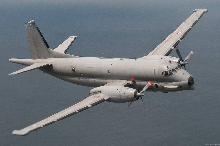 Avião cinza com dois motores a hélice voa sobe mar azul