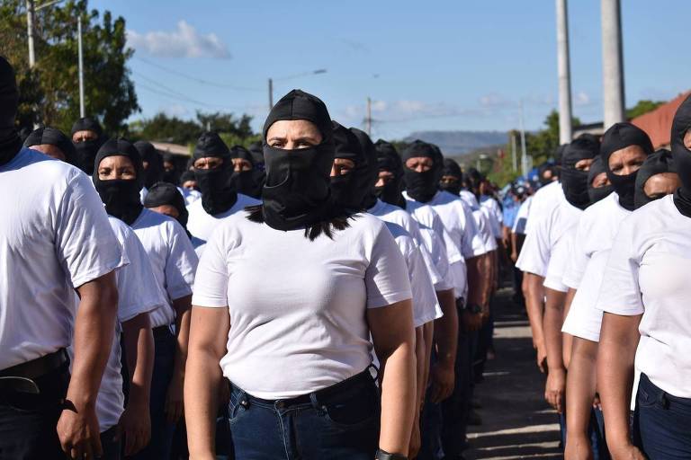 dezenas de mulheres enfileiras vestem camiseta branca， calça preta e têm o rosto coberto por balaclavas