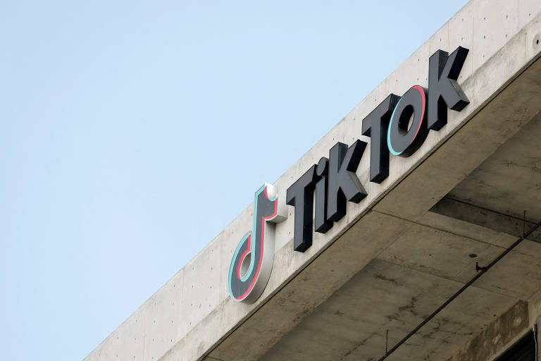 A imagem mostra o logotipo do TikTok em um edifício， com o fundo azul claro. O logotipo é composto pela palavra 039;TikTok039; em letras grandes e estilizadas， com um ícone colorido ao lado， que representa a marca.