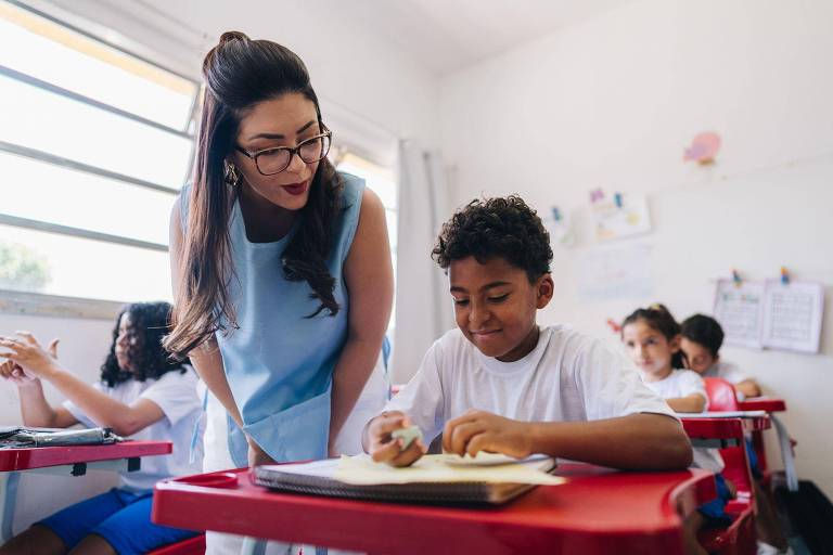 Uma professora ajuda um menino na escola
