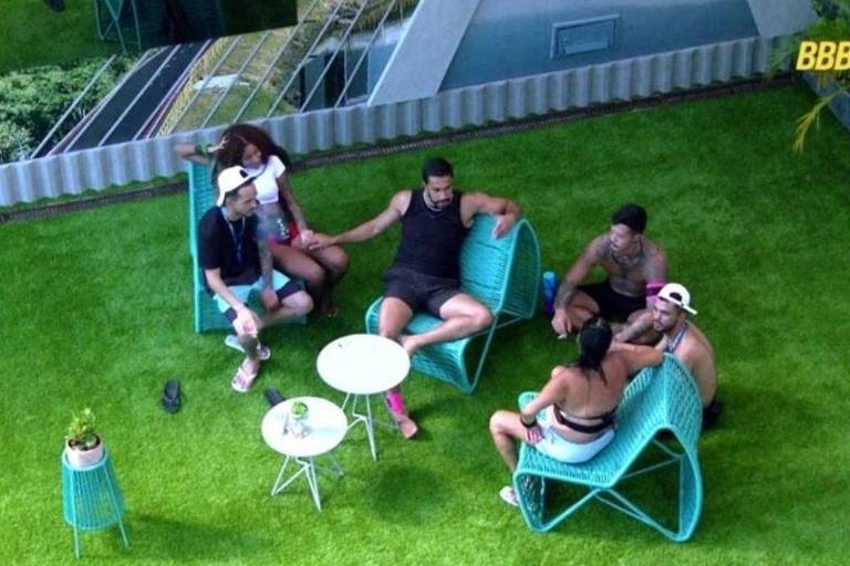 Em foto colorida, participantes de um reality show conversam na área externa da casa