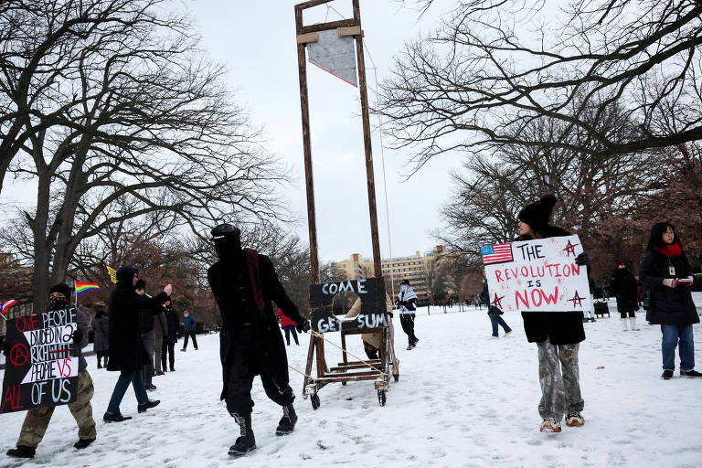 Uma pessoa puxa uma guilhotina de mentira em um protesto no Parque Malcolm X, em Washington