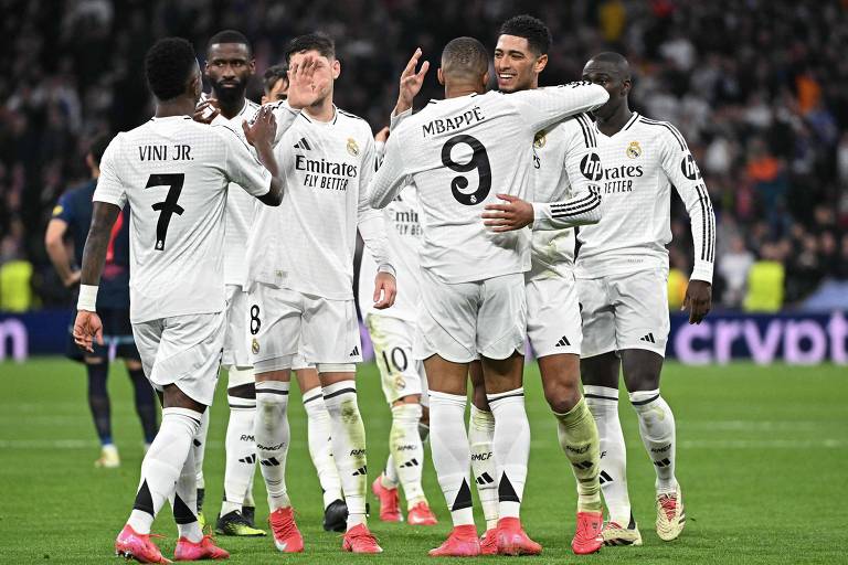 Seis jogadores do Real Madrid， entre os quais o brasileiro Vinicius Junior， comemoram com Mbappé， que usa a camisa com o número 9， o gol que o francês marcou na Liga dos Campeões da Europa contra o Salzburg， no estádio Santiago Bernabéu， na Espanha