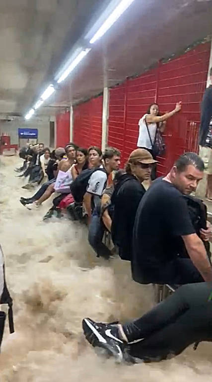 Passageiros ficam ilhados na estação Jardim São Paulo; eles tiveram de ficar em cima do corrimão para não serem levados pela água