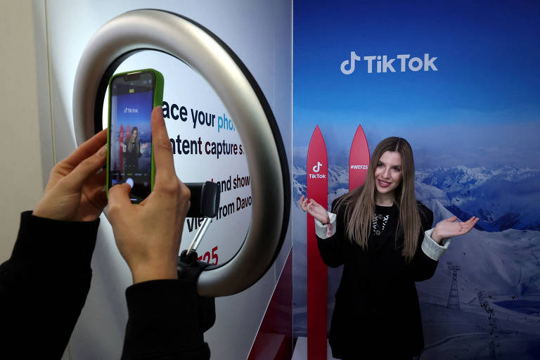 Mulher tira foto no espaço do TikTok no Fórum Econômico Mundial， em Davos 