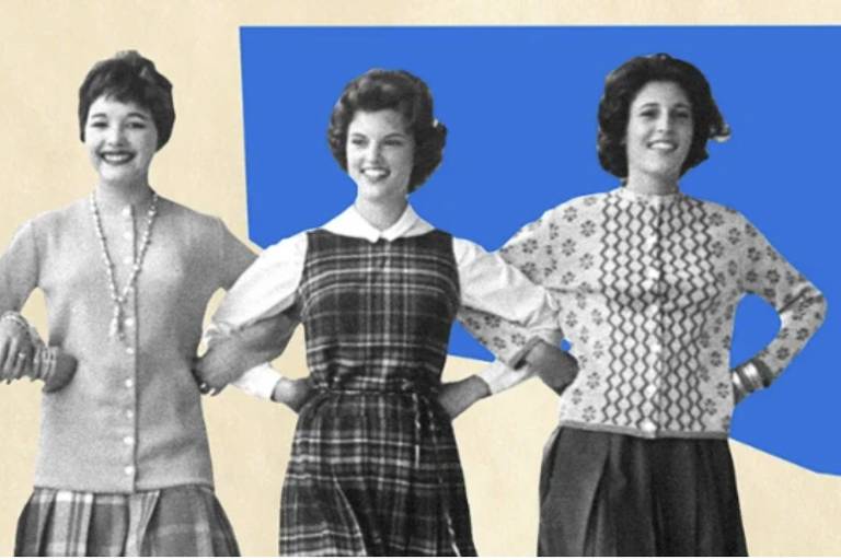 A imagem apresenta três mulheres em estilo vintage， posando lado a lado. A mulher à esquerda usa um suéter cinza e uma saia， a do meio veste um vestido xadrez e a da direita está com um suéter estampado. O fundo é de uma cor azul vibrante， contrastando com o tom neutro do restante da imagem.