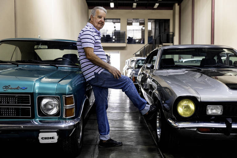 Imagem mostra o retrato do vendedor Carlos Roberto Dauria，75， entre um Opala e um Ford Maverick， na loja Eduardo Veículos Antigos， na alameda Barão de Limeira， onde ele trabalha há 57 anos