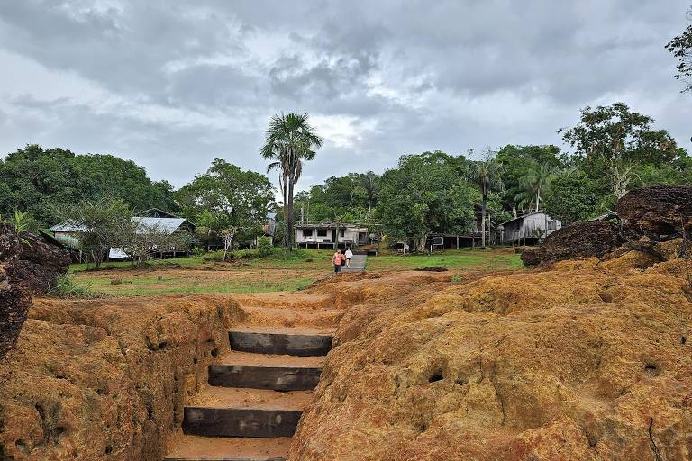 Degraus de terra e, acima, árvores e algumas casas de uma comunidade ribeirinha