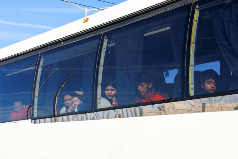 Crianças venezuelanas no interior de um ônibus olham pela janela 