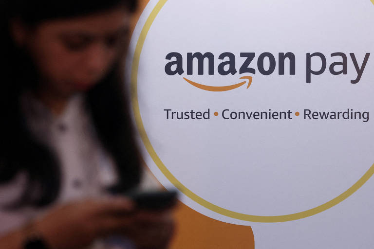 A imagem mostra uma parte de um logotipo do Amazon Pay， com as palavras 039;Trusted • Convenient • Rewarding039; em destaque. Ao fundo， uma pessoa está usando um celular， mas não é possível identificar detalhes sobre ela.
