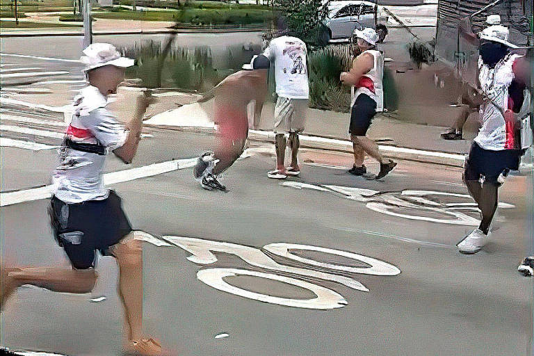 A imagem mostra um grupo de pessoas em uma rua， algumas delas vestindo camisetas brancas e bonés. Um homem no centro parece estar em uma posição defensiva， enquanto outros ao redor estão em movimento， alguns segurando objetos. O ambiente é urbano， com sinalização no chão indicando 039;20039;.