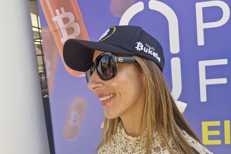 A imagem mostra uma mulher sorrindo， usando um boné preto com o símbolo do Bitcoin e óculos de sol. Ao fundo， há um painel roxo com a palavra 039;OPEN039; e ícones relacionados ao Bitcoin.