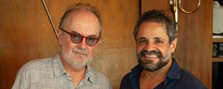 Em foto colorida， o cavaquinista Henrique Cazes e violonista Rogério Caetano posam para a câmera