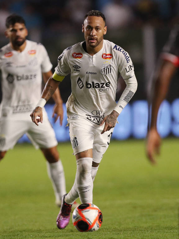 O atacante Neymar do Santos controla a bola durante a partida no campo.