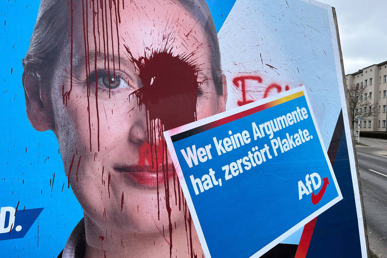 A imagem mostra um pôster político com a face de uma mulher， que está coberta por manchas de tinta vermelha. Um cartaz azul com texto em alemão está fixado no pôster， que diz: 039;Wer keine Argumente hat， zersört Plakate.039; O fundo é urbano， com edifícios visíveis