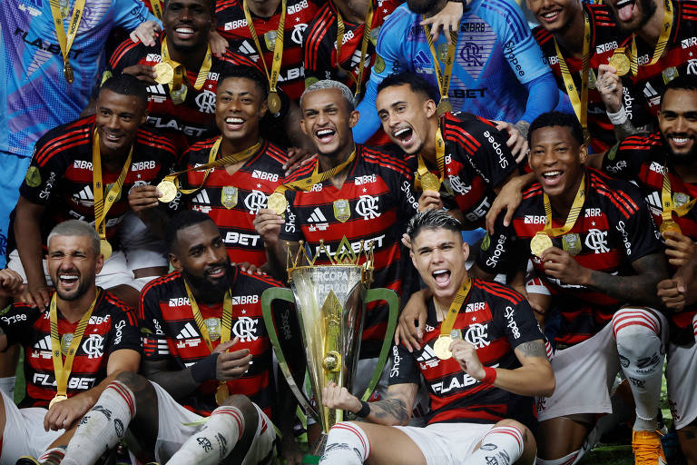 Sorridentes， vibrando e com medalhas no pescoço， jogadores do Flamengo festejam com a taça a conquista da Supercopa do Brasil de 2025， depois de vitória sobre o Botafogo no estádio Mangueirão， em Belém