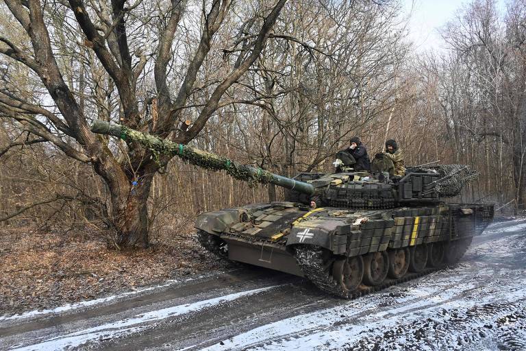 Tanque de guerra verde， com dois soldados em cima， em uma estrada com neve