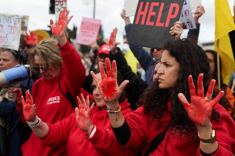 Mulheres de vermelho com as mãos pintadas da mesma cor em protesto 