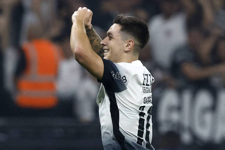 Com as mãos juntas， unidas， à frente da cabeça e sorrindo， Rodrigo Garro comemora gol pelo Corinthians contra o Vitória no Campeonato Brasileiro de 2024， no estádio de Itaquera， em São Paulo 