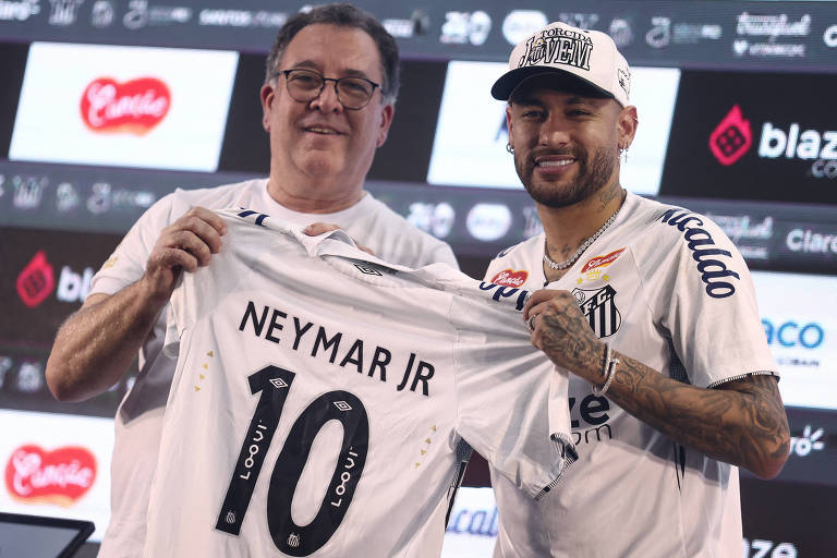 Usando boné e sorrindo， Neymar posa ao lado do presidente do Santos， Marcelo Teixeira， em seu em seu retorno ao clube do litoral paulista; os dois seguram uma camisa branca com o número 10 e a inscrição quot;Neymar Jrquot;