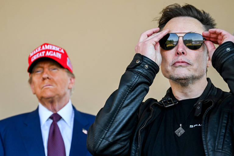 A imagem mostra duas Donald Trump e Elon Musk em um evento. À frente， Musk está com óculos escuros e uma jaqueta preta. Ao fundo， Trump veste um terno escuro e uma gravata vermelha， ele está com um boné vermelho com a frase: Make America Great Again