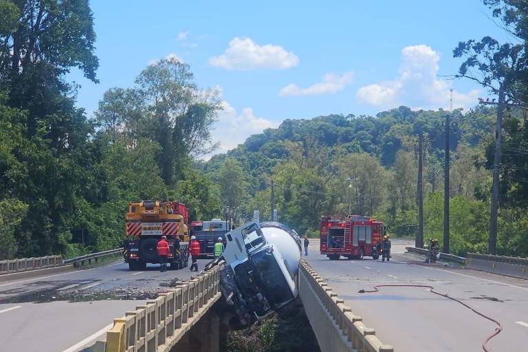 A imagem mostra um acidente de carro em uma estrada. Um veículo está capotado no meio da pista， enquanto caminhões de emergência estão presentes na cena.