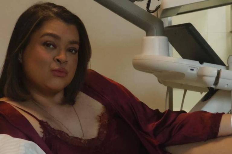 Mulher de roupa roxa olha para câmera
