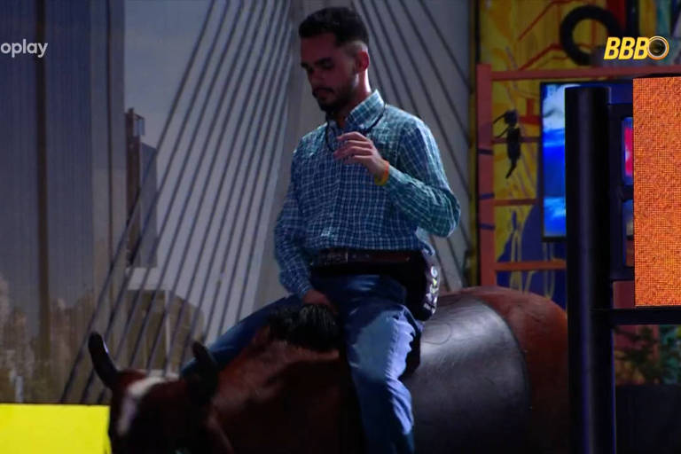 Homem vestido de camisa social monta um Touro mecânico 
