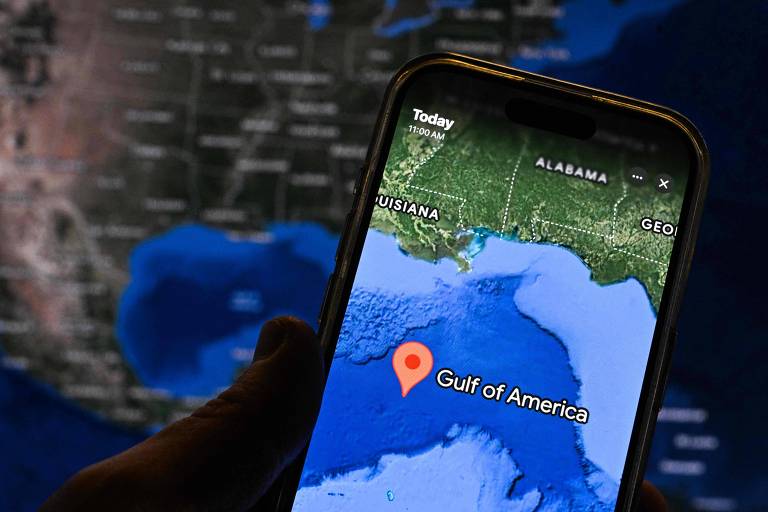 A imagem mostra um smartphone exibindo um mapa com a localização marcada como 'Gulf of America'. Ao fundo, há um mapa da região dos Estados Unidos, destacando os estados da Louisiana e Alabama.