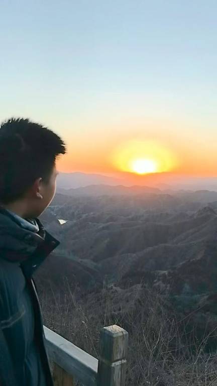 Estudante chinês Zhao Ray diante do pôr do Sol, na Grande Muralha, na China, em 12 de fevereiro de 2025