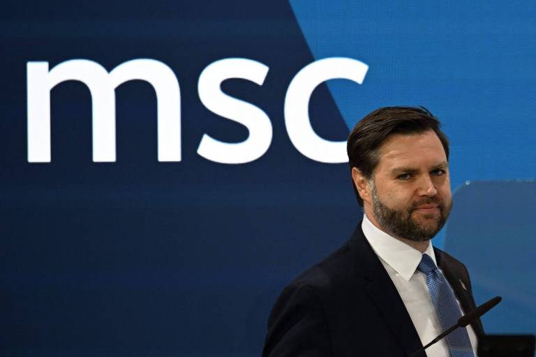 A imagem mostra um homem em um terno escuro， com cabelo castanho e barba， posando em frente a um fundo azul onde está escrito 039;msc039; em letras brancas. O homem parece estar em um evento ou conferência.