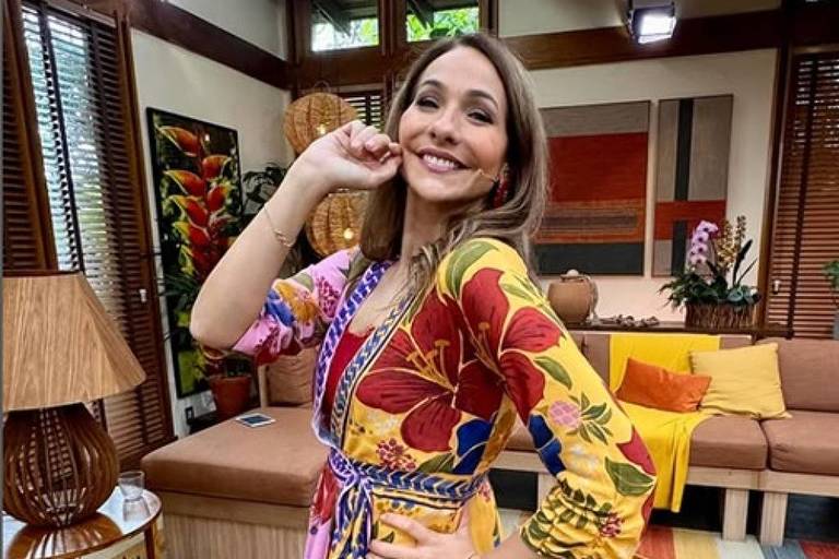 Em foto colorida, mulher de vestido estampado faz pose para foto