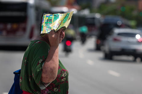 SAO PAULO, SP - 18/02/2025 - Na foto: Mulher se protege com jornal para fugir do sol no Largo da Batata. Paulistanos enfrentam mais um dia de forte calor. (Foto: Danilo Verpa/Folhapress, COTIDIANO) ORG XMIT: 611322