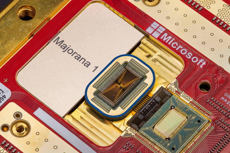 A imagem mostra uma placa de circuito vermelho com um chip quântico no centro， identificado como 039;Majorana 1039;. O chip está cercado por componentes eletrônicos e conectores metálicos. O logotipo da Microsoft é visível no canto superior direito da placa.