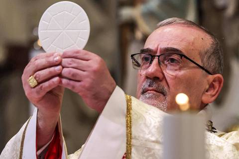 TOPSHOT - Latin Patriarch of Jerusalem Pierbattista Pizzaballa holds a communion wafer above the altar during the Christmas midnight Mass at the Catholic Church of Saint Catherine, in the Nativity Church Complex, in the biblical city of Bethlehem in the occupied West Bank on December 25, 2024. (Photo by Alaa BADARNEH / POOL / AFP)