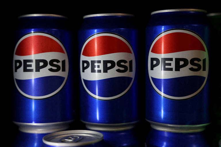 A imagem mostra três latas de refrigerante Pepsi alinhadas. As latas são de cor azul com o logotipo da Pepsi em destaque， que consiste em um círculo vermelho e branco com uma faixa azul. A lata mais à esquerda está parcialmente visível， enquanto as outras duas estão em foco. No fundo， há uma lata de refrigerante em posição horizontal.