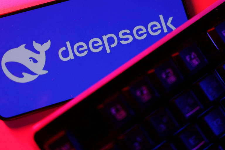 A imagem mostra um logotipo da empresa Deepseek em um fundo azul. O logotipo é acompanhado por um ícone de uma baleia. Abaixo do logotipo， há um teclado visível， que está em um ambiente iluminado com luzes em tons de vermelho e azul.