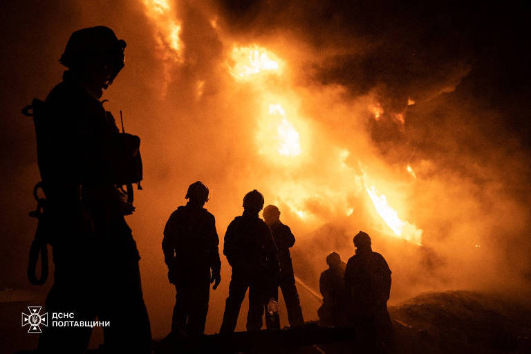 Bombeiros no escuro em frente a chamas de incêndio