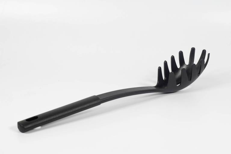 A imagem mostra um utensílio de cozinha de plástico preto， especificamente uma colher para macarrão (ou espaguete). O design do utensílio inclui uma parte côncava com dentes ao redor， permitindo segurar e servir massas longas com mais facilidade. O cabo é longo e levemente curvado， proporcionando um manuseio ergonômico. O fundo da imagem é branco， criando um contraste com o utensílio escuro.