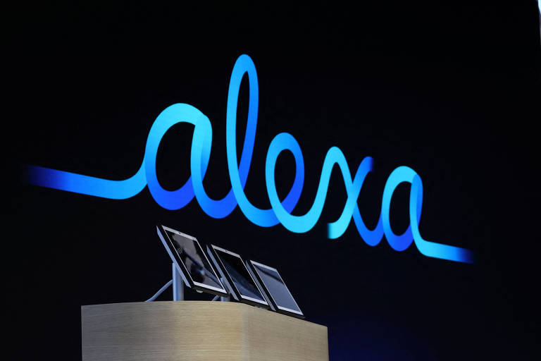 A imagem apresenta o logotipo da Alexa em letras cursivas， iluminado em azul， contra um fundo preto. Na parte inferior， há uma base de madeira com três dispositivos eletrônicos de tela plana dispostos em uma linha.