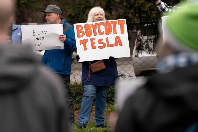 Manifestantes em Seattle; cartaz diz "boicote a Tesla"