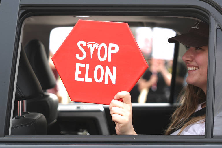 Manifestante segura placa escrita 'Pare Elon' em ato contra a administração de Donald Trump na Califórnia