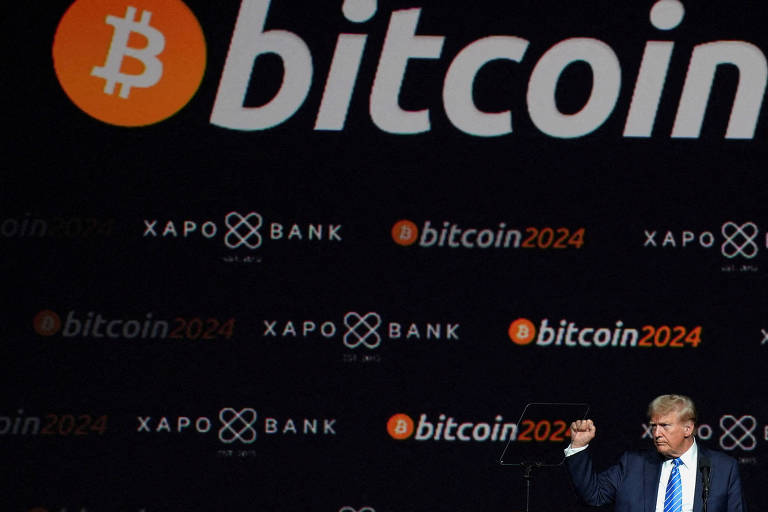 A imagem mostra um palco com um fundo escuro onde estão escritos 039;bitcoin039; e 039;Xapo Bank039; em letras grandes. Um símbolo de Bitcoin em laranja está presente. À frente， um homem de terno azul e gravata levanta o punho， aparentemente em um gesto de celebração ou afirmação.