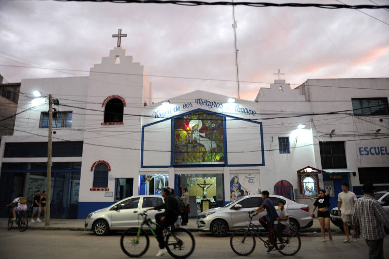 Fachada da paróquia Caacupé durante o anoitecer, localizada no coração da Villa 21-24, onde fiéis se reúnem para rezar pelo pontífice argentino
