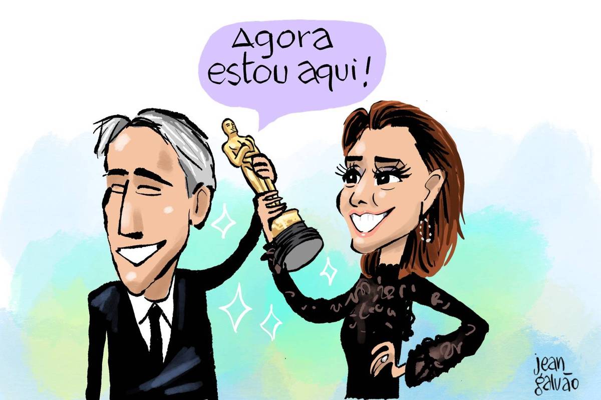 A charge de Jean Galvão publicada na Folha mostra o diretor Walter Salles e a atriz Fernanda Torres segurando a estatueta do Oscar acima da cabeça. Eles estão sorrindo enquanto num balão de fala vindo da estatueta está escrito: “Agora estou aqui!”